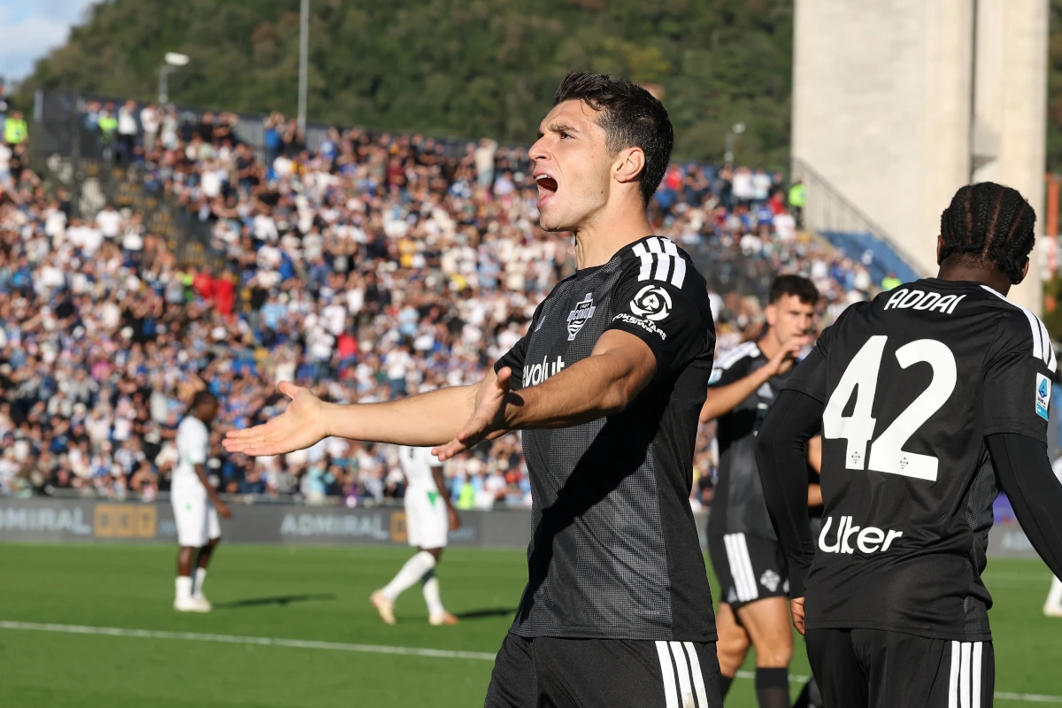 Tasos Douvikas, in Como's black kit, spreads his arms in celebration after opening the scoring against Sassuolo at the Sinigaglia on 24 October 2026.
