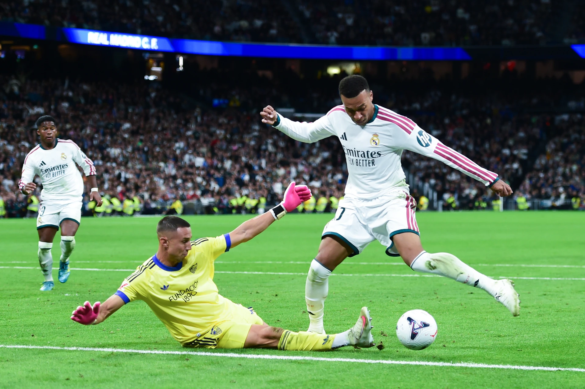 Ảnh tư liệu ngày 18/10/2026: Mbappé trong áo trắng Real Madrid chuẩn bị dứt điểm trong khi thủ môn Sevilla áo vàng lao ra cản phá.