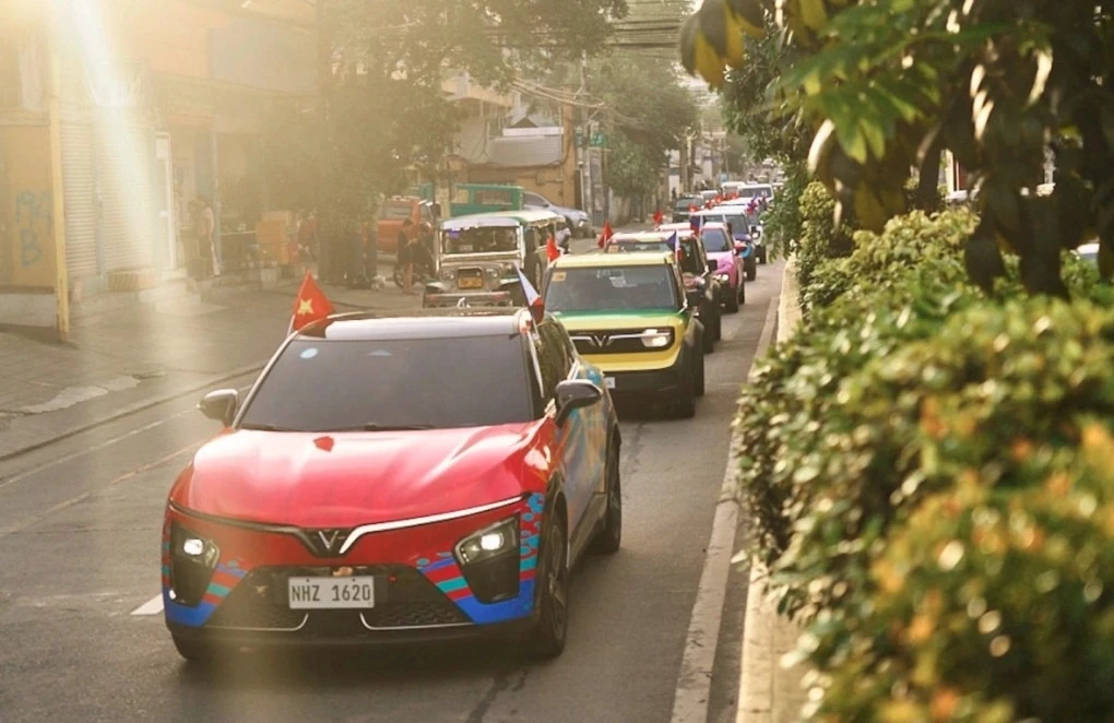 A convoy of VinFast cars drives down a street in the Philippines, led by a red car.