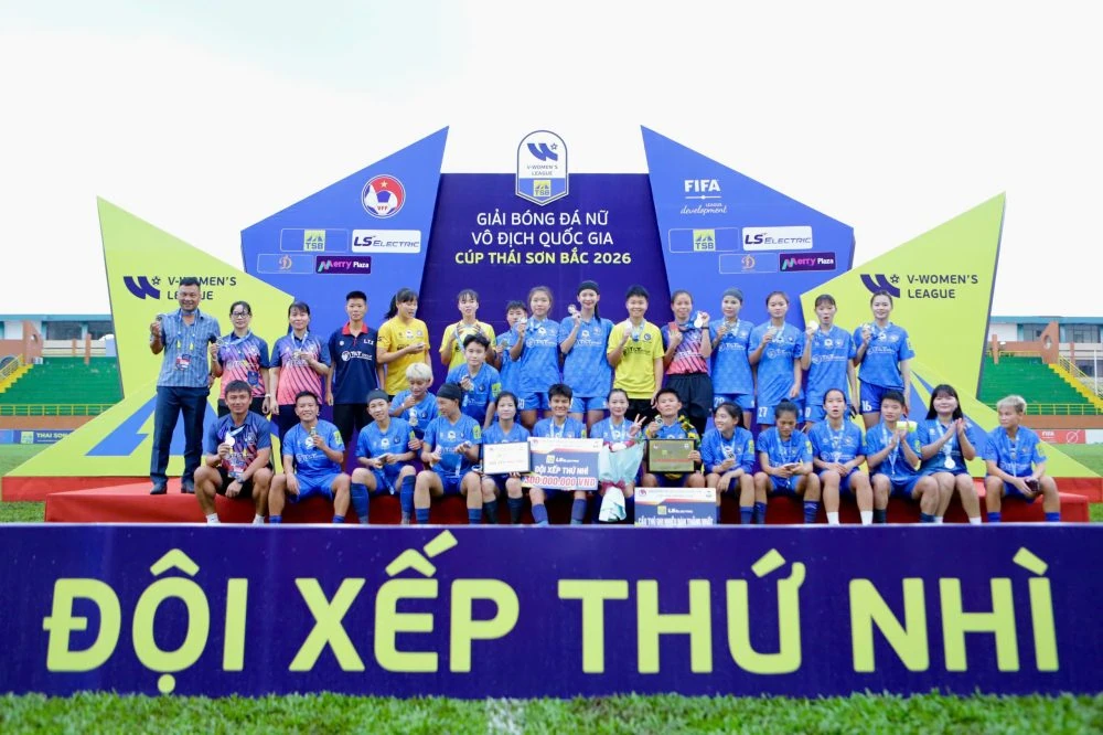 Thái Nguyên T&T players and staff in blue pose on the award podium behind a banner reading Đội xếp thứ nhì (second place).