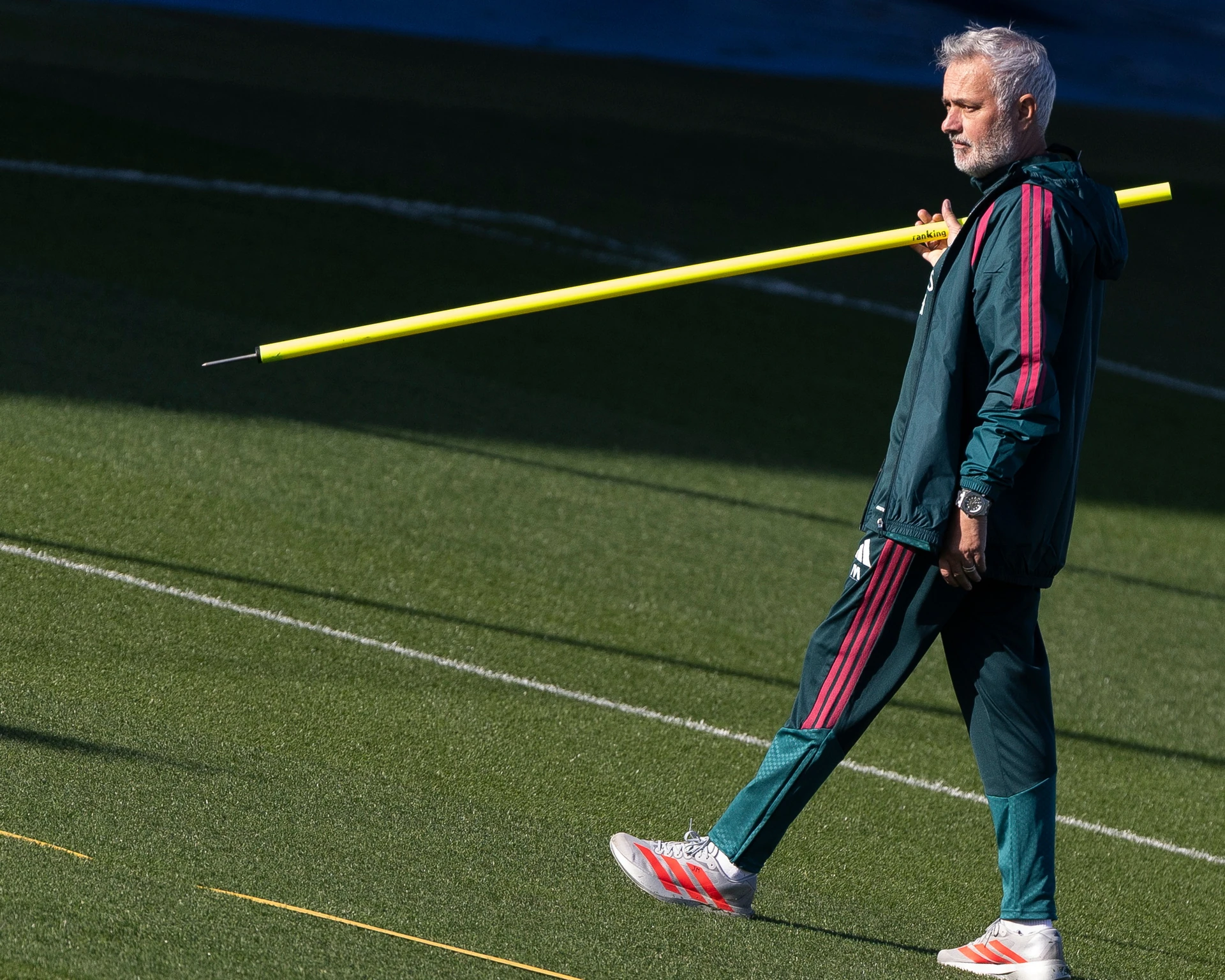HLV José Mourinho mặc đồ tập Real Madrid vác cọc tập màu vàng trên vai, bước đi trên sân tập