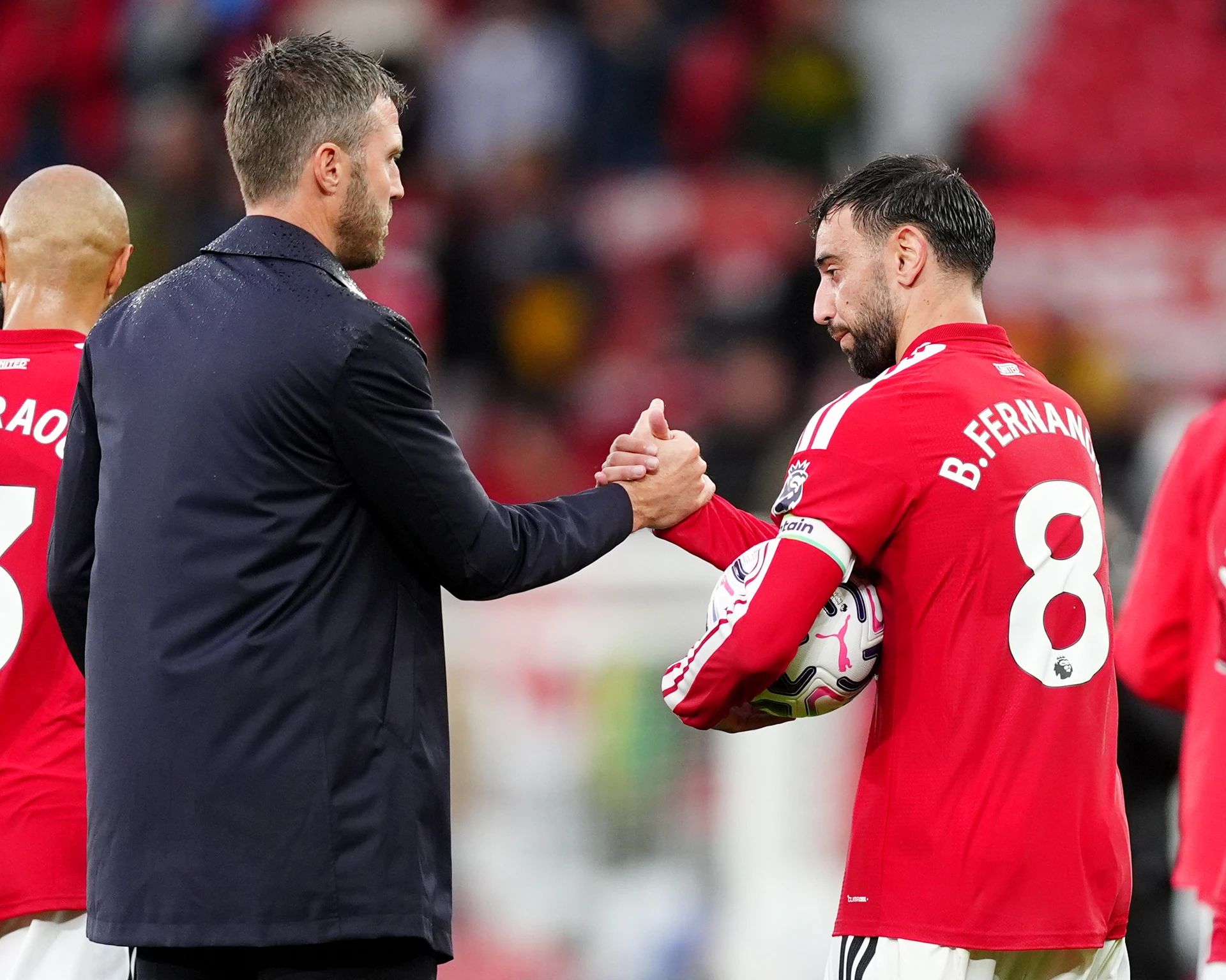HLV Michael Carrick bắt tay đội trưởng Bruno Fernandes của Manchester United trên sân.