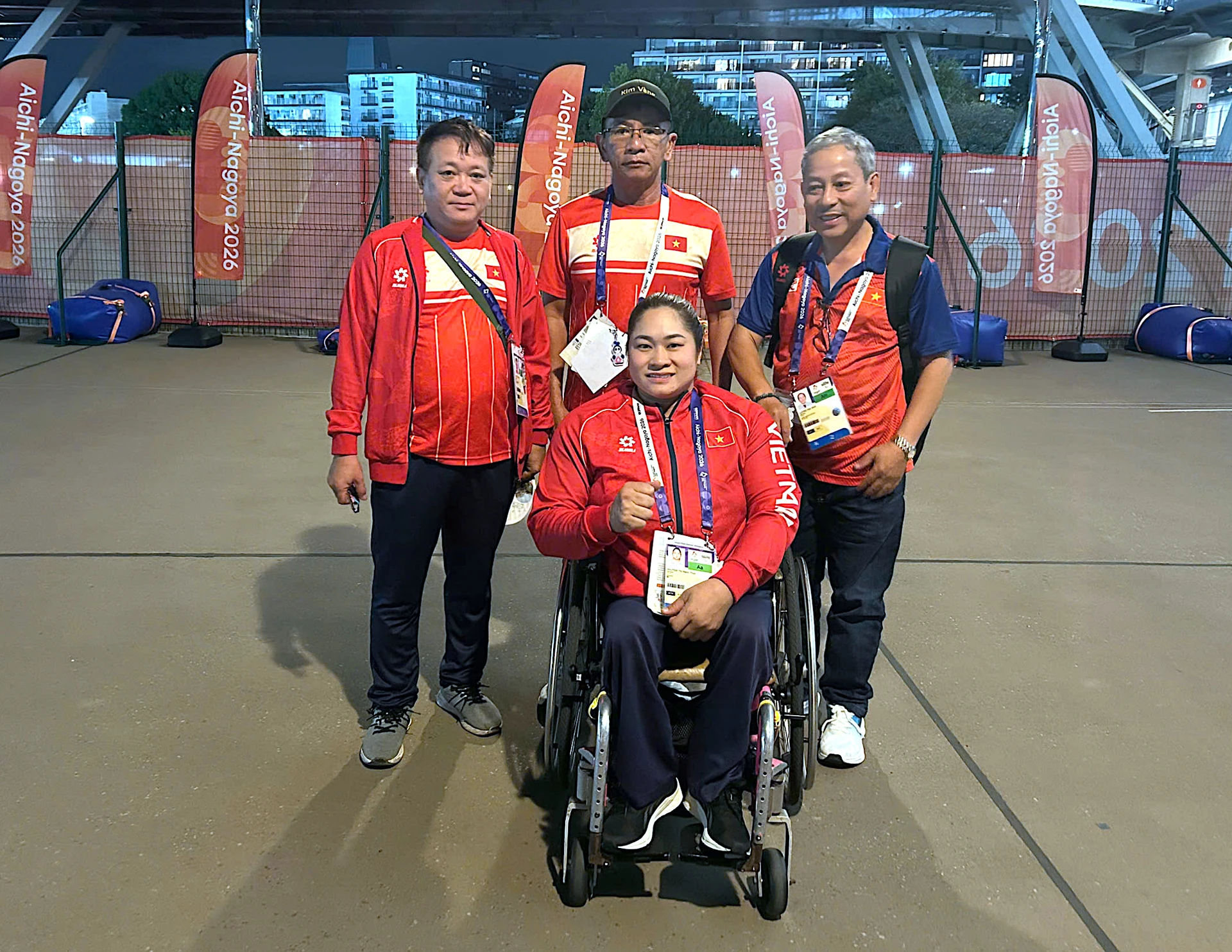 Ngọc Thúy, seated in a wheelchair, poses with coaches and team staff of the Vietnam delegation at the Asian Para Games.