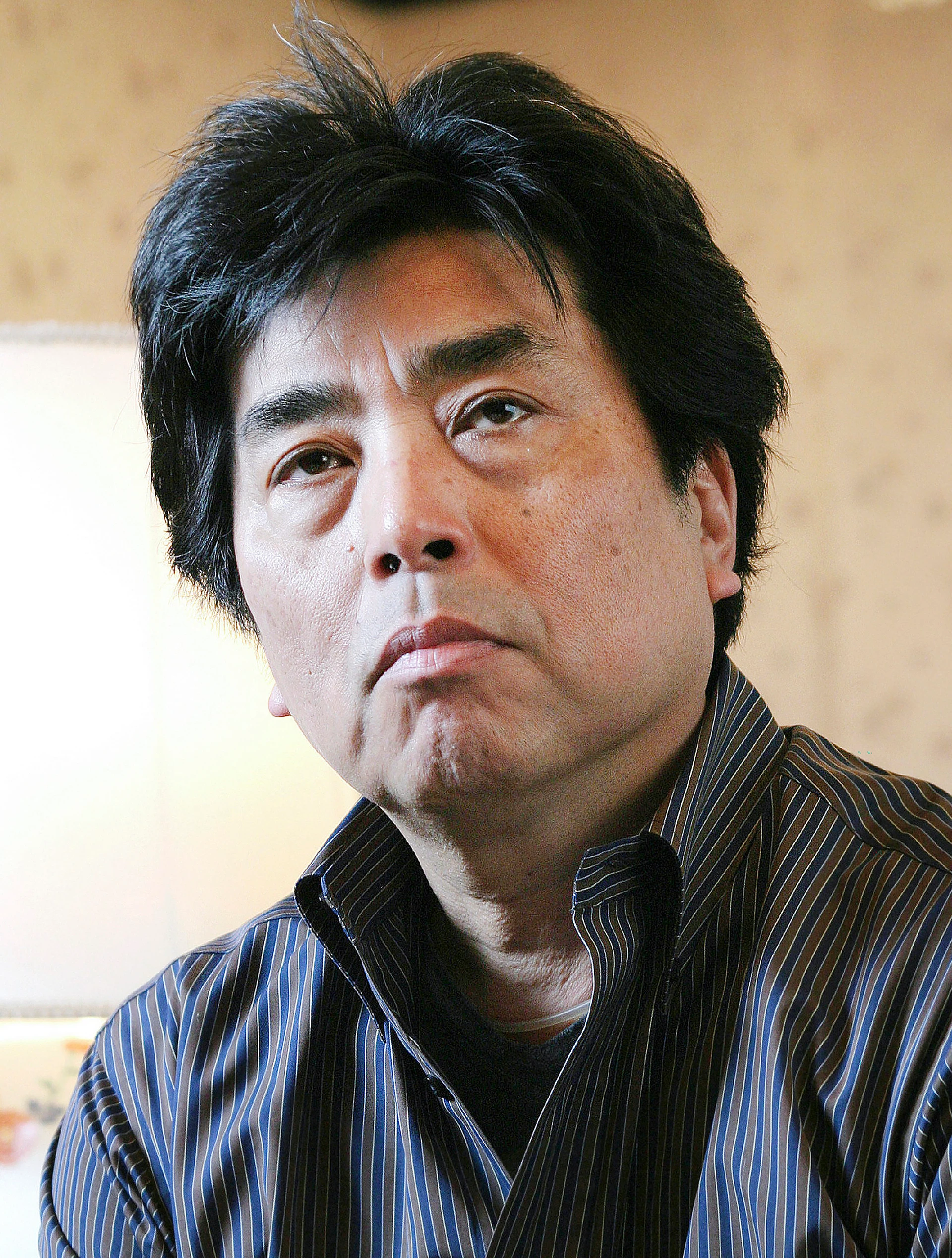 Portrait of Japanese novelist Ryu Murakami in a striped shirt, looking to one side