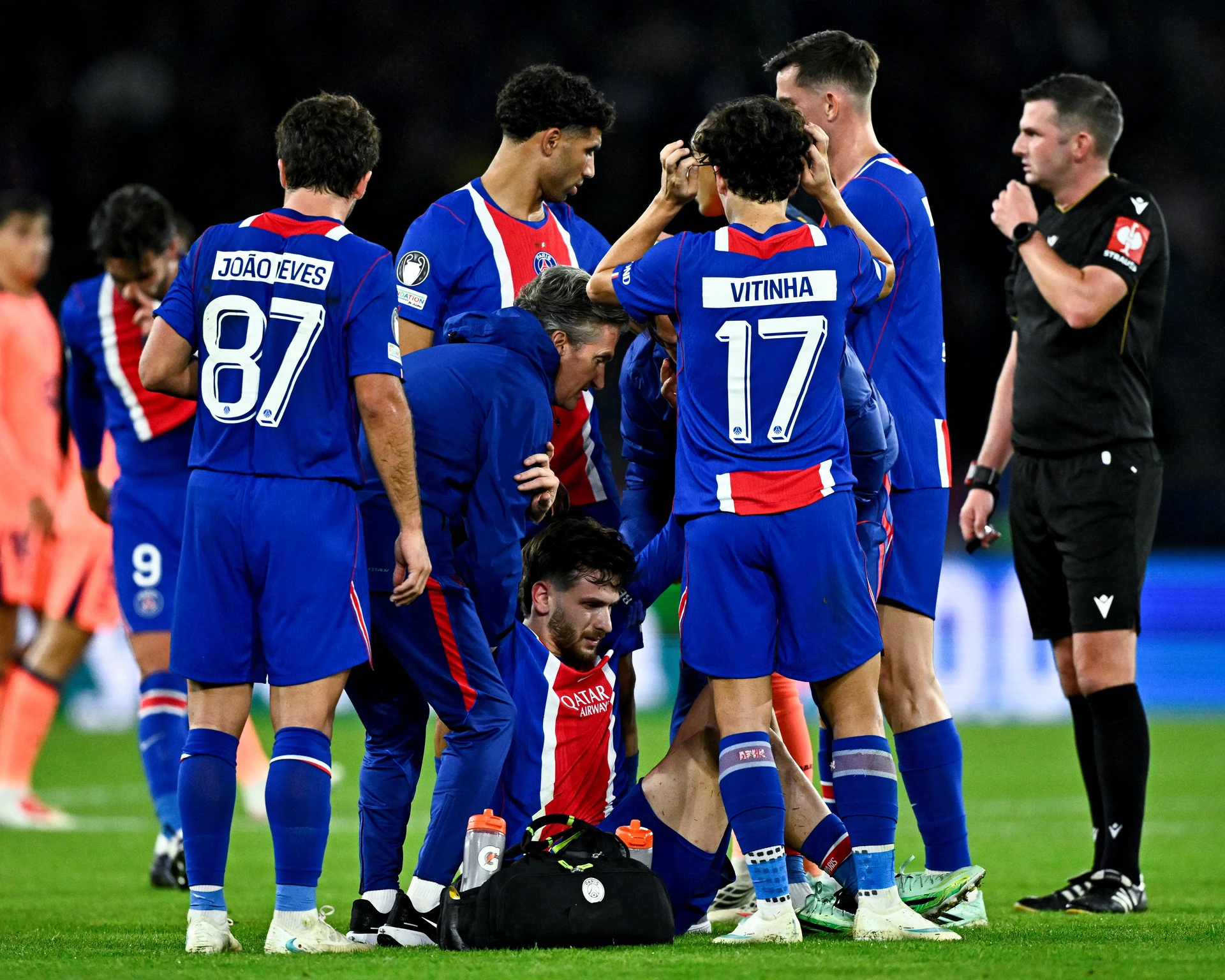 Khvicha Kvaratskhelia receives treatment after injuring his knee in PSG's match against Barcelona.