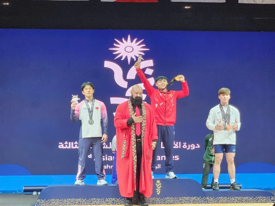 File photo: Nguyễn Thành Duy (in red) raises his gold medal on the podium in front of an Asian Youth Games backdrop