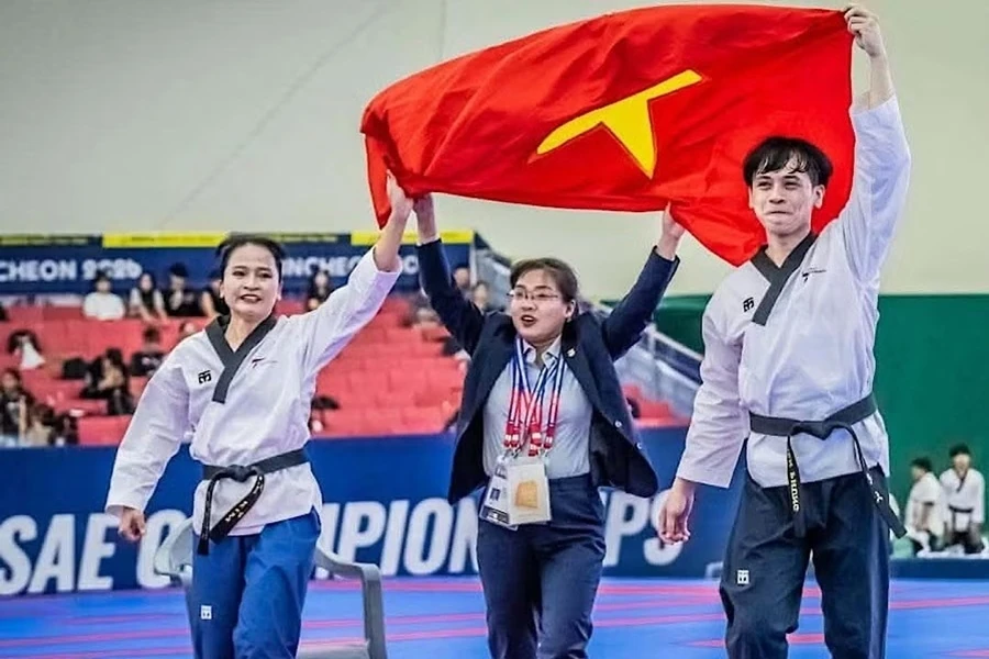 Nguyễn Thiên Phụng and Nguyễn Thị Lệ Kim hold up Vietnam's flag after their taekwondo victory.