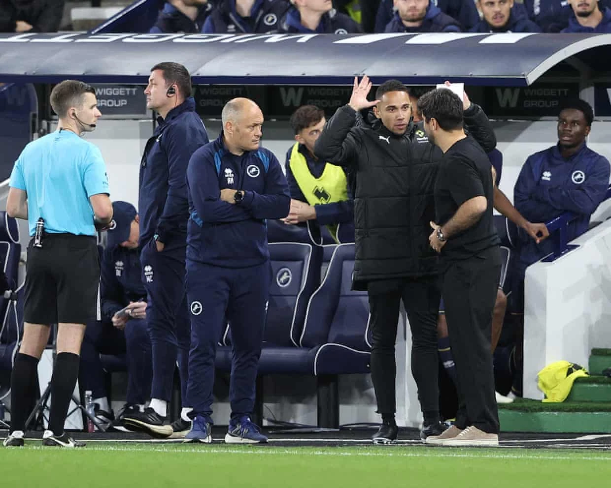 Trọng tài thứ tư trao đổi với ban huấn luyện khi trận Millwall–Swansea bị tạm dừng.