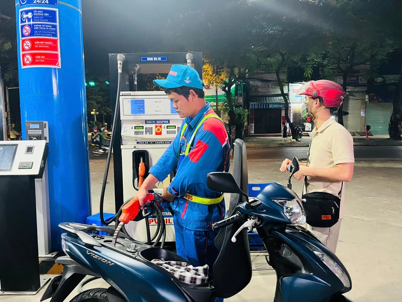 Illustration photo: a petrol station attendant refuels a motorbike in the evening.